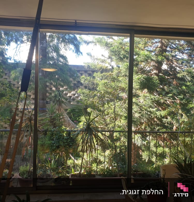 חלון זכוכית גדול עם נוף של עצים ירוקים